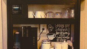 A kitchen with a coffee maker, a microwave, and a decorative sign that reads "Mighty your coffee be strong and your Monday be short."