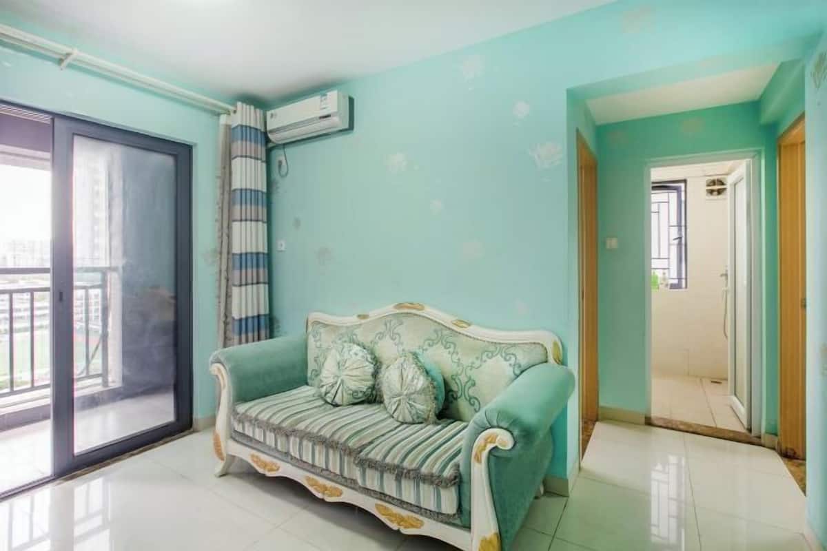 A room with a sofa, a sliding glass door, and an air conditioning unit.