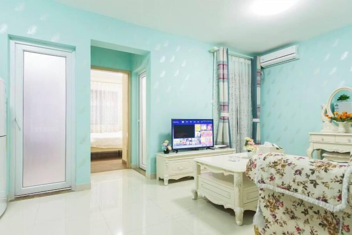 A bedroom with a bed, a desk, a TV, and a wardrobe.