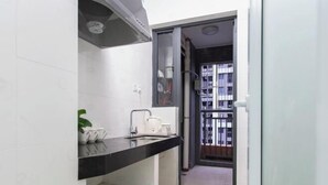 Una cocina moderna con encimera negra, azulejos blancos y una pequeña planta.