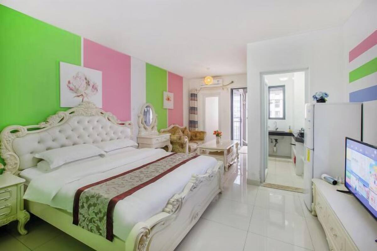 A bedroom with a large bed, a television, and a bathroom visible through an open door.