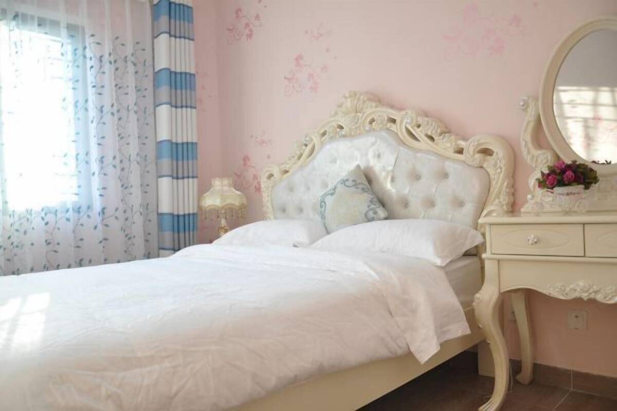 A bedroom with a bed, a dresser, a mirror, and a window with curtains.