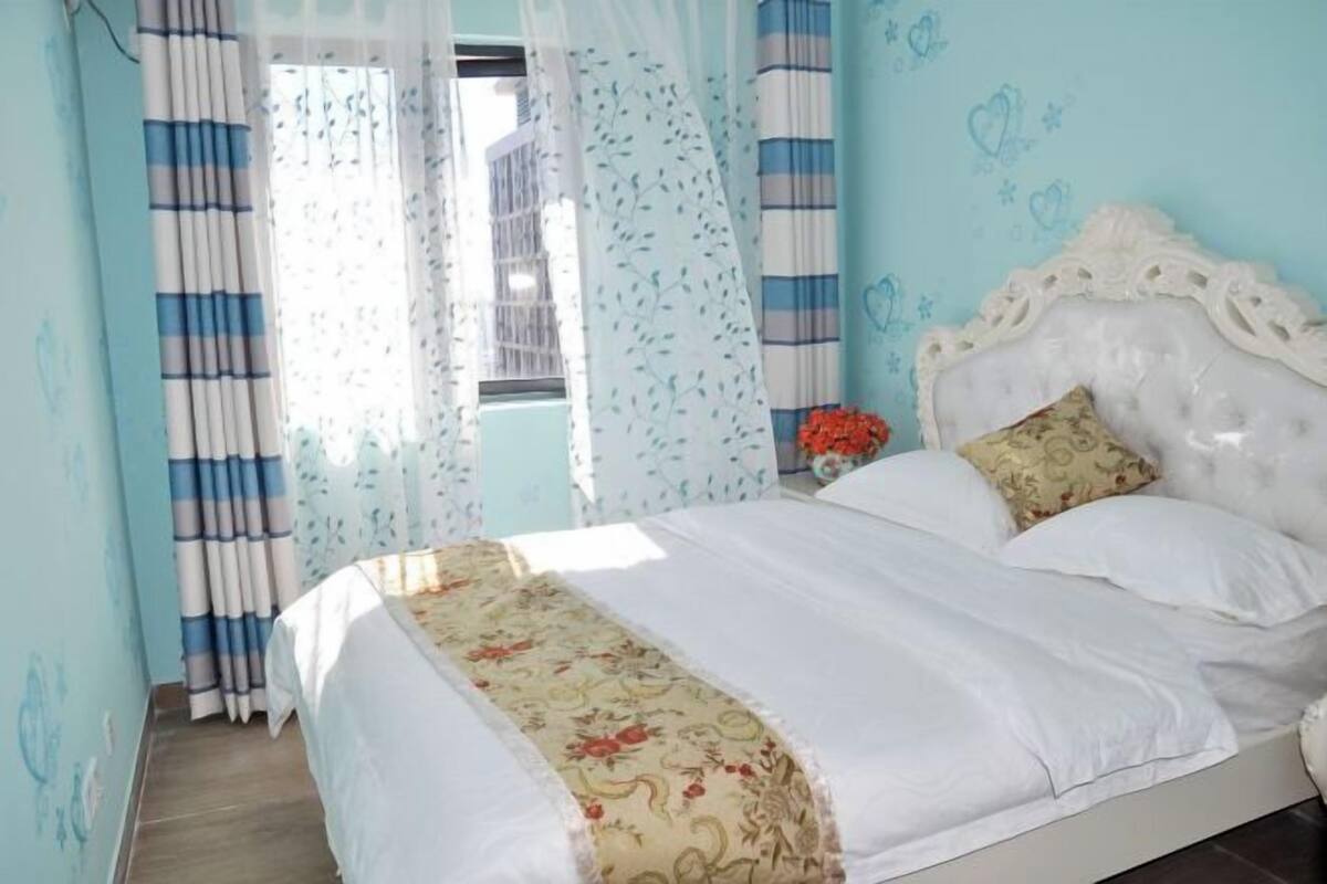 A bedroom with a bed, curtains, a headboard, and a window.
