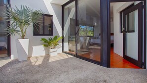 A modern house with a glass door leading to a patio area.