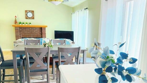 A dining area with a wooden table and chairs, a fireplace, and a decorative plant.