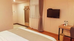 A hotel room with a bed, a TV, a desk with a chair, and a coat rack. - GreenTree Inn Kunshan Shimao Square Hotel (Kunshan)