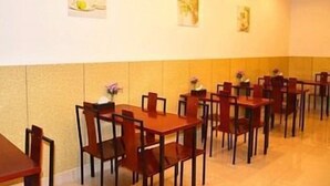 A dining area with tables and chairs, a vase with flowers, and framed artwork on the wall. - GreenTree Inn Kunshan Shimao Square Hotel (Kunshan)