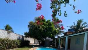 Une piscine dotée d’une terrasse carrelée, entourée d’une pelouse verdoyante et d’un mur de pierre.