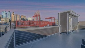 A rooftop terrace with a view of a city skyline, a red construction structure, and a small building with a door. - Center City Philadelphia rooftop (Philadelphia)