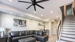 A modern living room with a sectional sofa, a dining area, and a staircase. - Center City Philadelphia rooftop (Philadelphia)