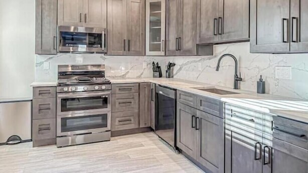 A modern kitchen with stainless steel appliances, grey cabinetry, and a marble backsplash. - Center City Philadelphia rooftop (Philadelphia)
