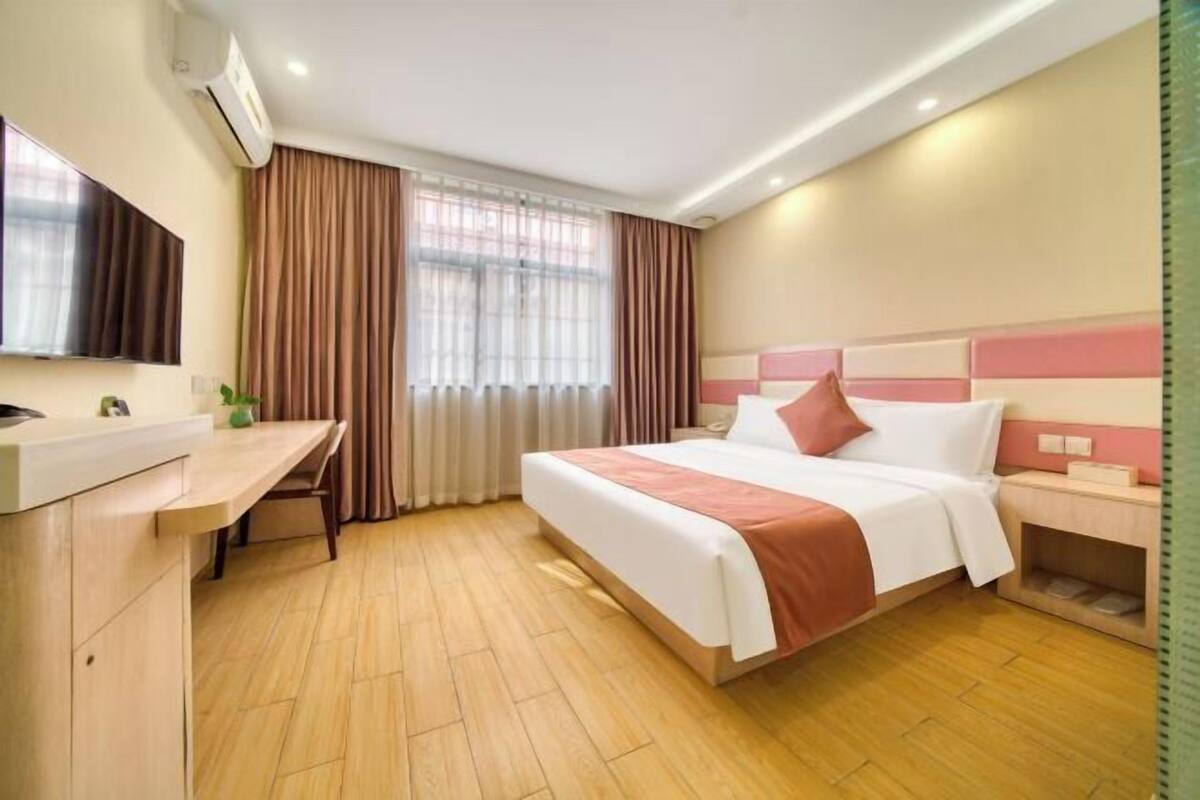 A hotel room with a bed, bedside table, desk, and a television.