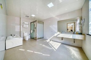 A modern bathroom with a large bathtub, two sinks, a glass shower enclosure, and a large mirror.