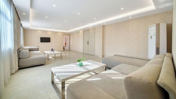 Ein modernes Wohnzimmer mit einer Couch, einem Couchtisch und einem an der Wand montierten Fernseher.