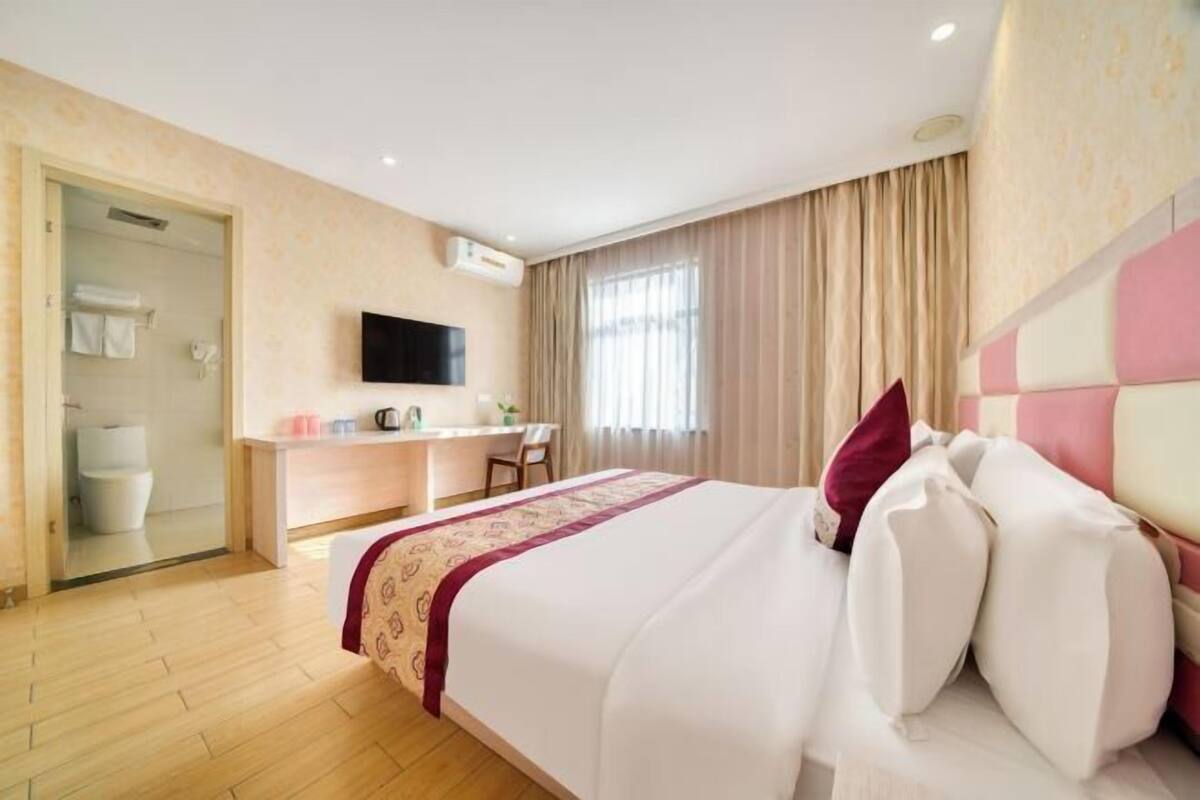 A hotel room with a bed, a desk, a television, and a shower area.