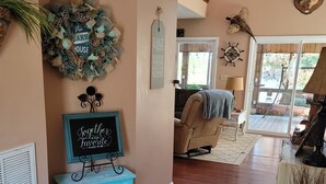 A cozy living room with a wooden floor, a blue accent table, a decorative wreath, and a sign that reads "Together is our favorite place to be."
