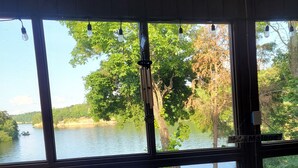 A room with a large window overlooking a lake, wicker furniture, and a sign reading "Lake Malone".