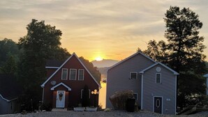 A gravel driveway leading to two houses with a sunset in the background.