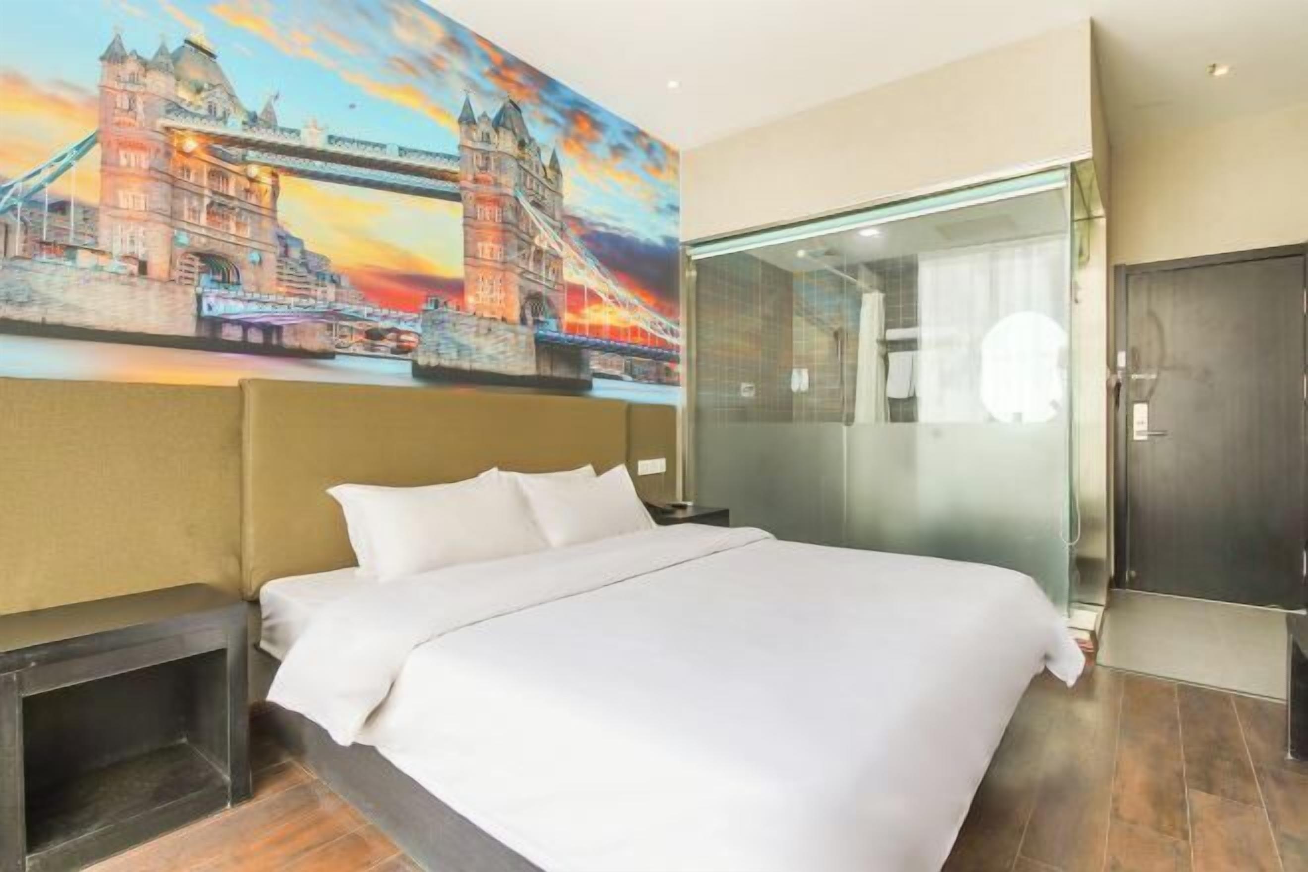 Ein Hotelzimmer mit einem großen Bett, einer Duschkabine aus Glas und einem Wandbild einer Brücke.
