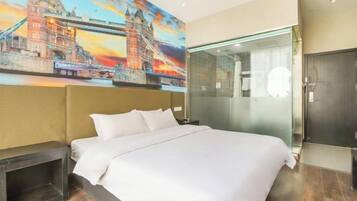 Ein Hotelzimmer mit einem großen Bett, einer Duschkabine aus Glas und einem Wandbild einer Brücke.