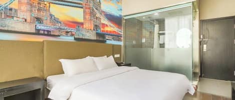 A hotel room with a large bed, a glass shower enclosure, and a mural of a bridge.