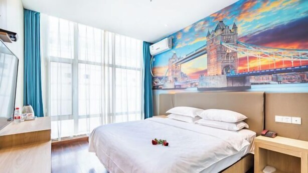 A hotel room with a bed, a desk, a chair, a window with curtains, and a wall mural of a bridge. - City 118 Chain Inn Qingdao Zhengyang Road Liqun (Qingdao)