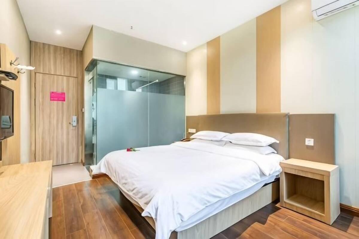 Una habitación de hotel moderna con cama, escritorio, armario y zona de ducha.