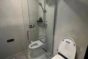 A glass-enclosed shower stall with a handheld showerhead and a toilet with a digital display. - City 118 Chain Inn Qingdao Zhengyang Road Liqun (Qingdao)