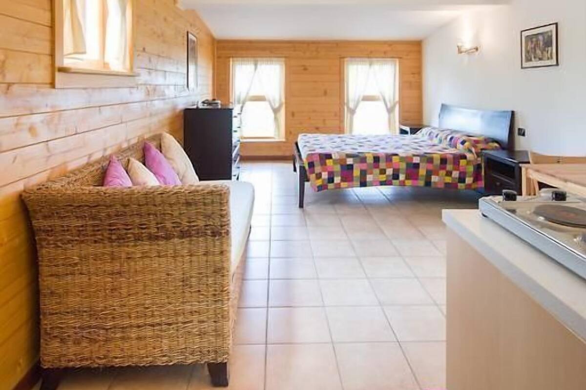 Um quarto aconchegante com uma cama, um sofá e uma pequena cozinha.