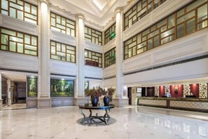 A spacious lobby with high ceilings, large windows, and a reception desk. - Shunhe Zaozhuang Hotel (Zaozhuang)