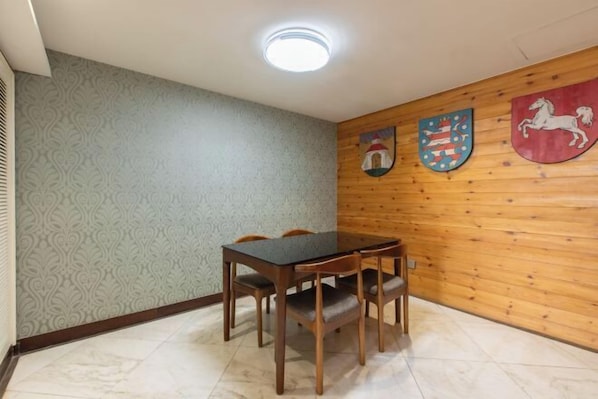A dining area with a wooden table and chairs, patterned wallpaper, and wooden paneling on the walls. - Shunhe Zaozhuang Hotel (Zaozhuang)
