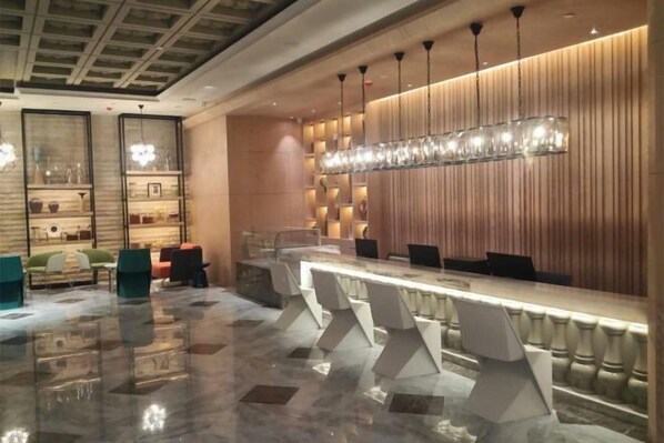 A modern hotel lobby with a long reception desk, comfortable seating, and a decorative light fixture. - Shunhe Zaozhuang Hotel (Zaozhuang)