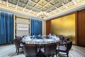A conference room with a round table, chairs, and a projector screen. - Shunhe Zaozhuang Hotel (Zaozhuang)