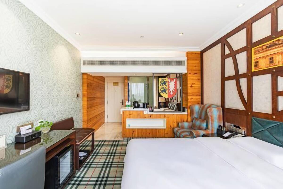 Ein Hotelzimmer mit einem Bett, einem Schreibtisch mit Computer, einem Stuhl, einem Spiegel und einer Holzvertäfelung.