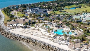 An aerial view of a coastal resort with a large swimming pool, multiple guest villas, and a golf course. - Luxury Villa, Club Access, Beach, Pet-Friendly (Seabrook Island)