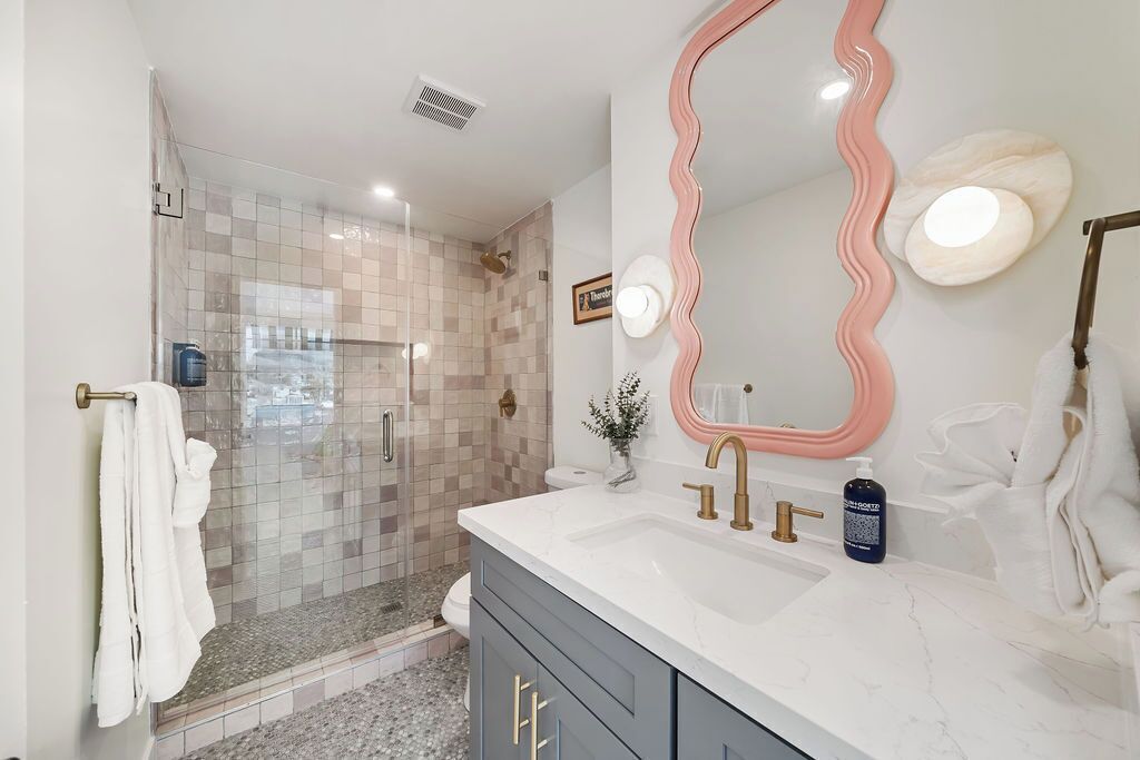 A modern bathroom with a shower, vanity, and a large mirror.