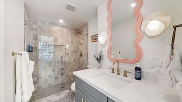 A modern bathroom with a shower, vanity, and a large mirror.