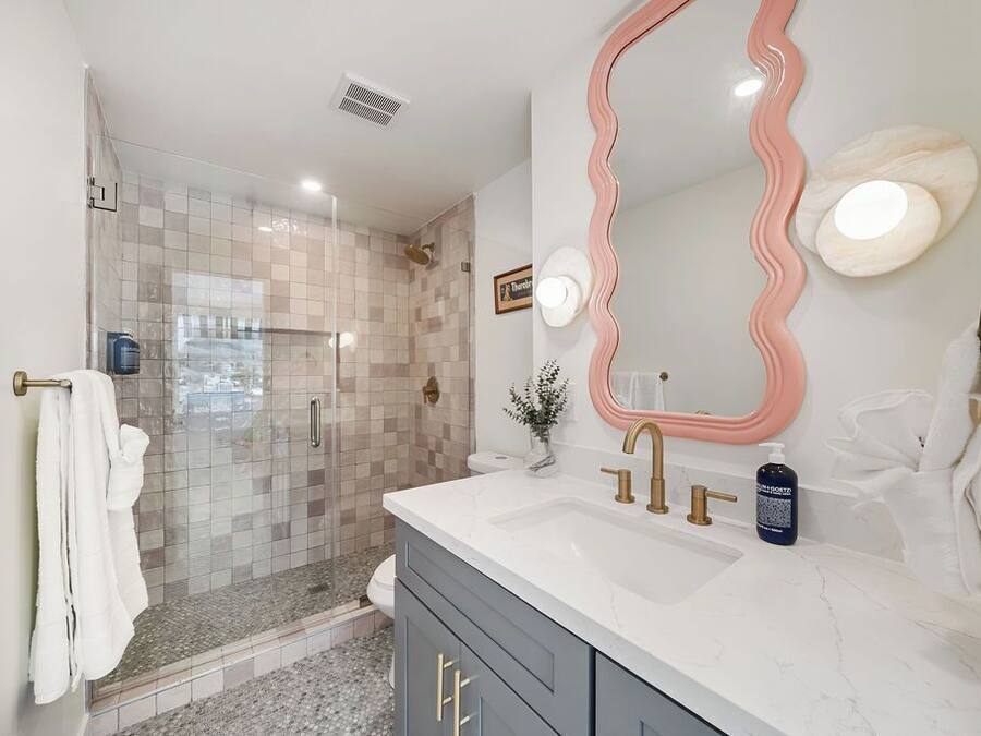 A modern bathroom with a shower, vanity, and a large mirror.