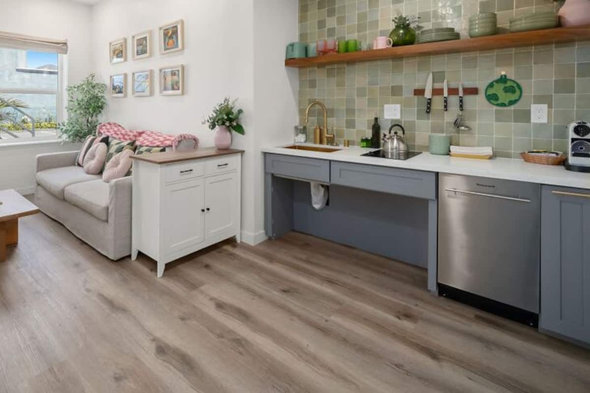 Una cocina moderna con armarios grises, lavavajillas de acero inoxidable y salpicadero de azulejos.