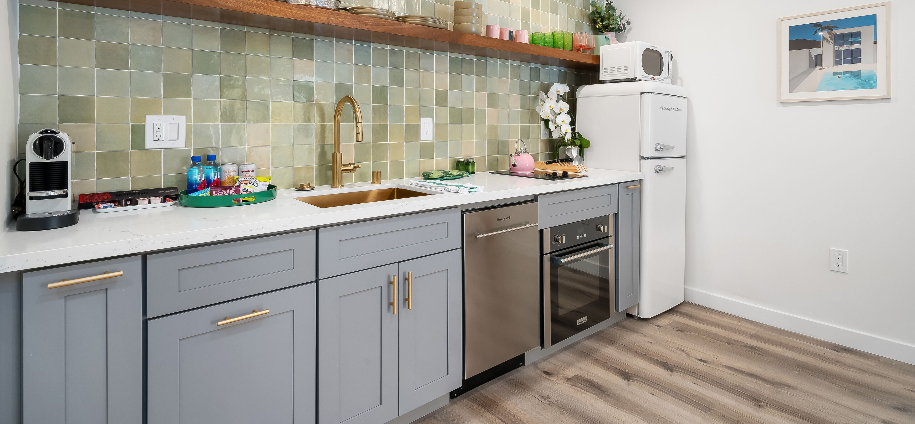 A modern kitchen with grey cabinets, a stainless steel oven, a dishwasher, and a microwave.