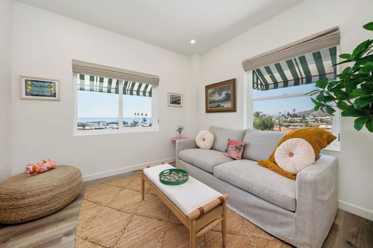 Una sala de estar con un sofá, un banco y vista al mar.