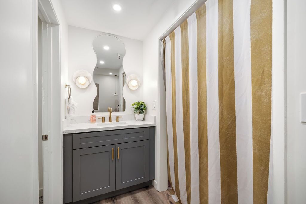 Een moderne badkamer met een wastafel, twee wasbakken, een spiegel en een douchegordijn.