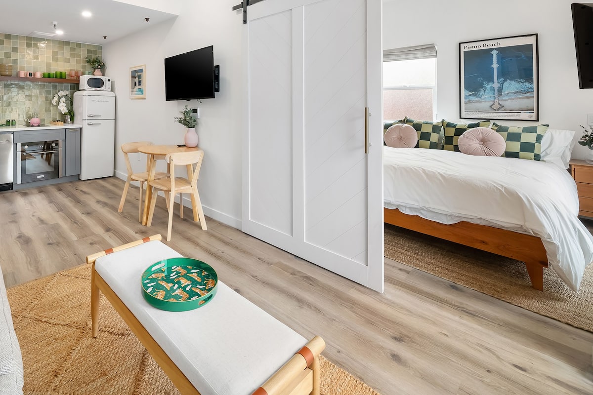 Una habitación moderna y bien iluminada con kitchenette, comedor y zona de dormitorio.
