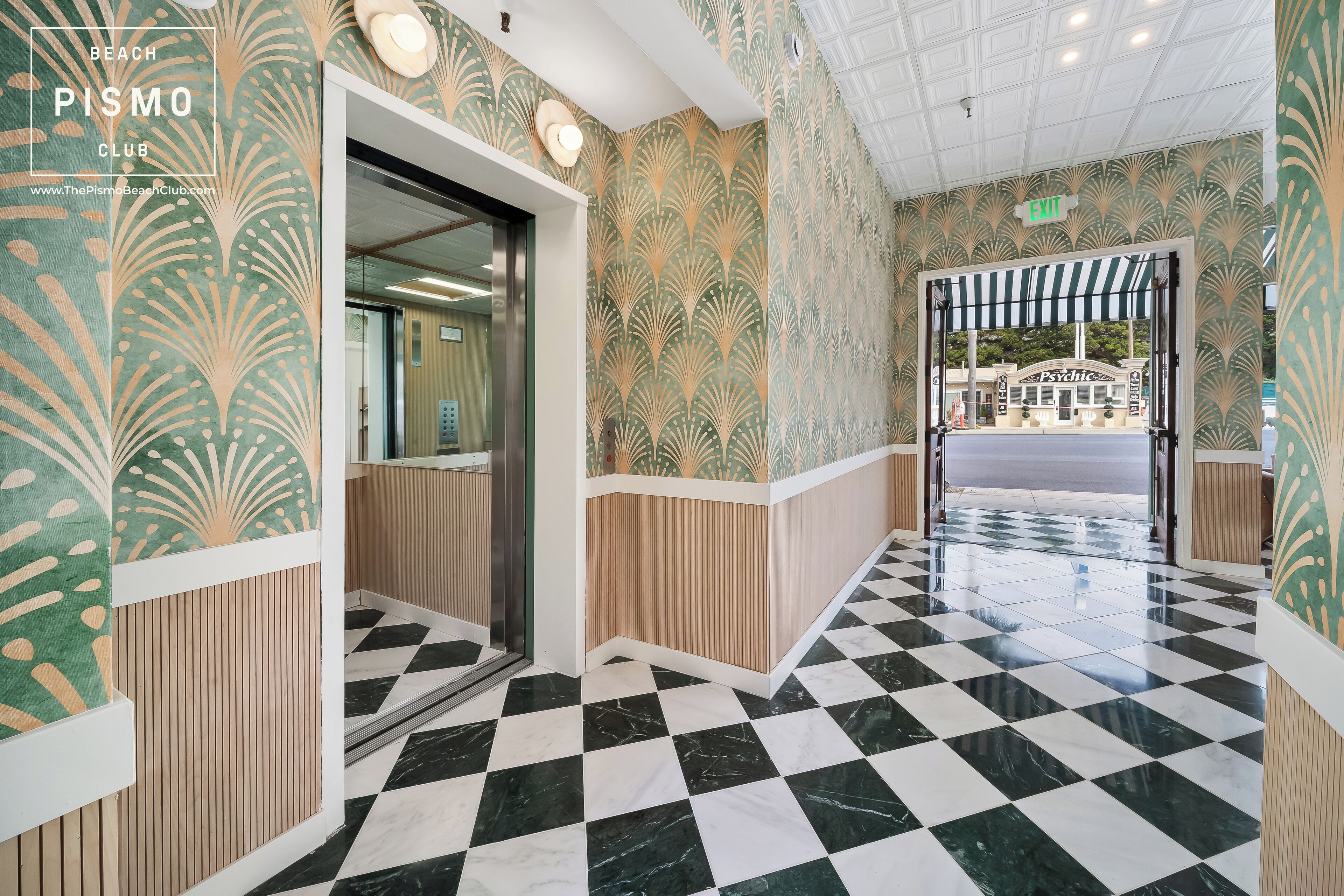 Un hall d’entrée avec un sol à carreaux, des murs décorés de motifs et un panneau indiquant la sortie.