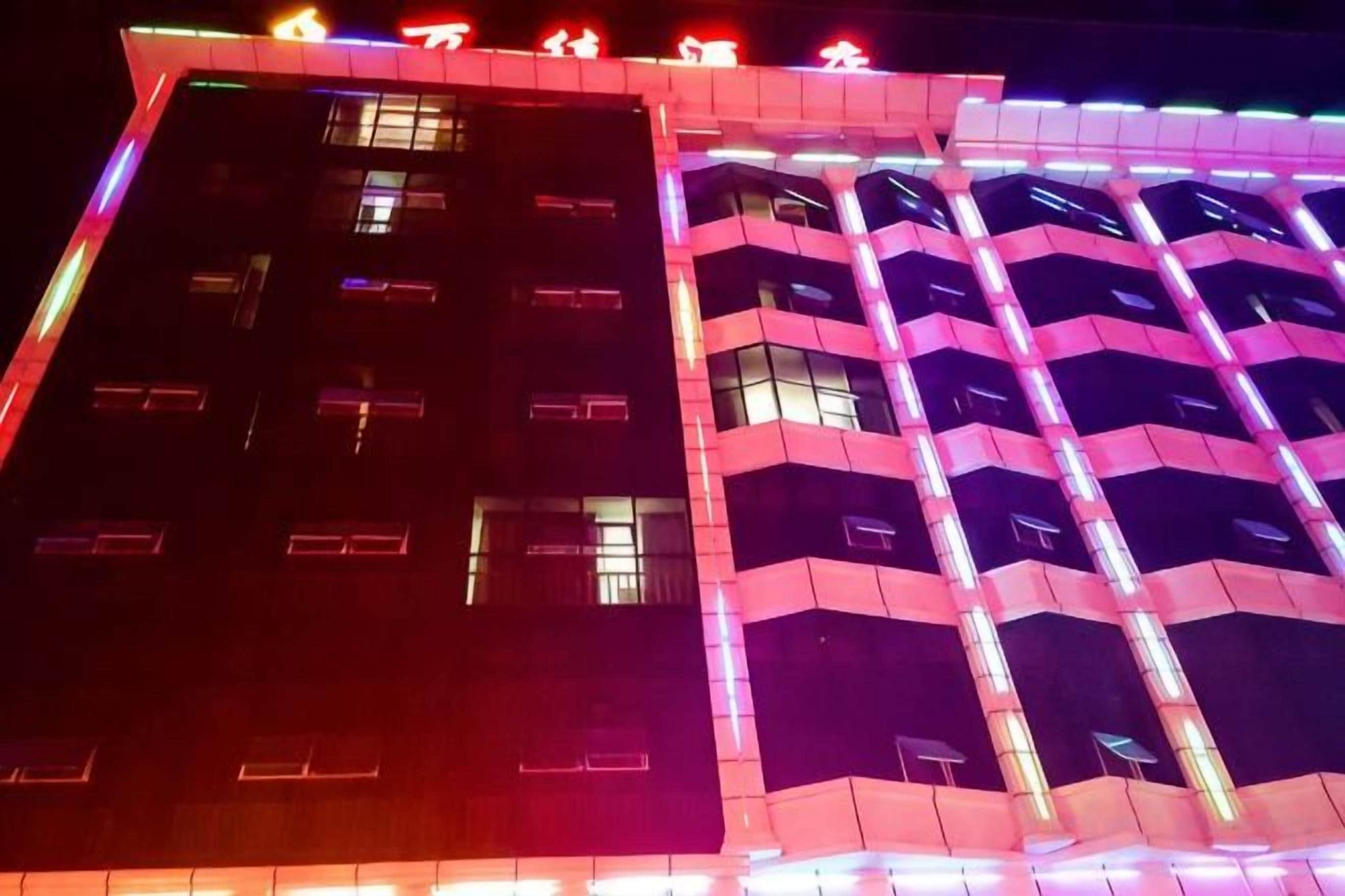 Un edificio a più piani con un caratteristico motivo a zig-zag delle finestre e una serie di insegne illuminate nella parte superiore.
