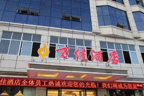 A hotel building with a prominent red sign and a logo. - Wanjia Hotel (Lincang)