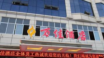 A hotel building with a prominent red sign and a logo.