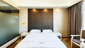 A hotel room with a large bed, a bedside table, a chair, and a view of the city. - Wanjia Hotel (Lincang)