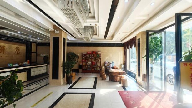 A hotel lobby with a reception desk, seating area, and large windows. - Wanjia Hotel (Lincang)