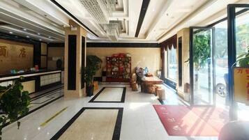 A hotel lobby with a reception desk, seating area, and a large window.